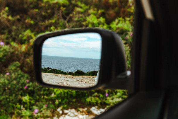 αντανάκλαση της θάλασσας στον πίσω καθρέφτη του αυτοκινήτου. οδικό ταξίδι. καλοκαιρινές διακοπές - Φωτογραφία, εικόνα