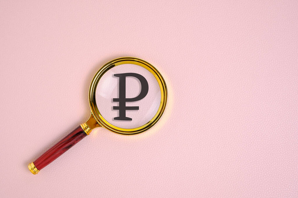 Ruble symbol under magnifying glass, on pink background - Фото, изображение