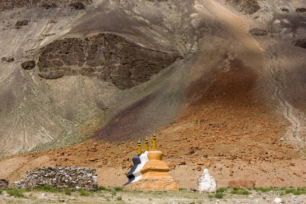 Tibetan Buddhist stupas on the barren slopes below high rocky mountain in the wilderness of the Zanskar region in Ladakh in the Indian Himalaya. - Fotografie, Obrázek
