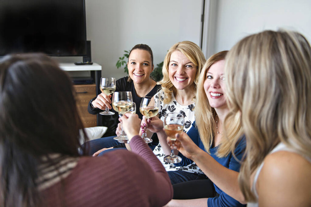 Five mature women toast and celebrating their meeting on the sofa - Foto, afbeelding