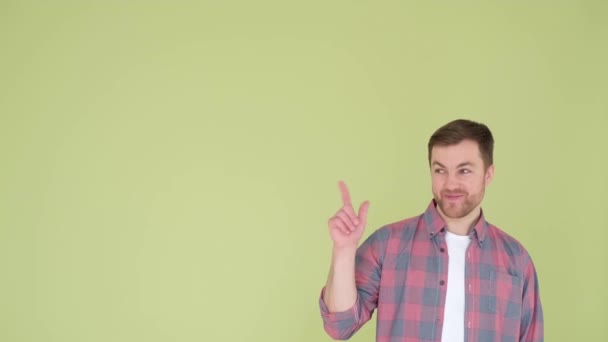 Un chico guapo de aspecto europeo en una camisa muestra su dedo hacia el espacio publicitario - Metraje, vídeo