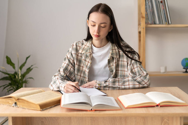hardworking american college student studying at home, studying with writing reference book, writing homework while studying at home school, high school student in bright classroom, education concept - Foto, Imagen
