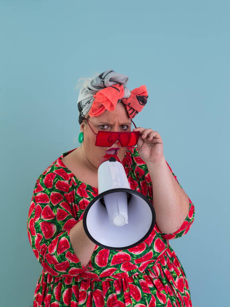 Funny plus size woman posing isolated on cyan background studio portrait. Screaming in a megaphone. People emotions lifestyle concept. Mock up copy space.  - Фото, изображение