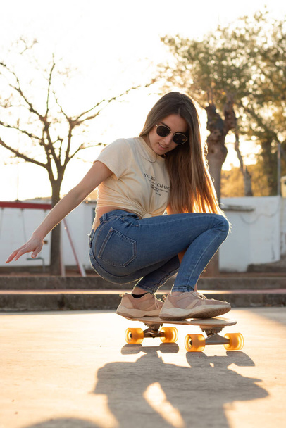 Backlit photography of an amazing young teenage girl rolling her longboard in a sporty way - Zdjęcie, obraz