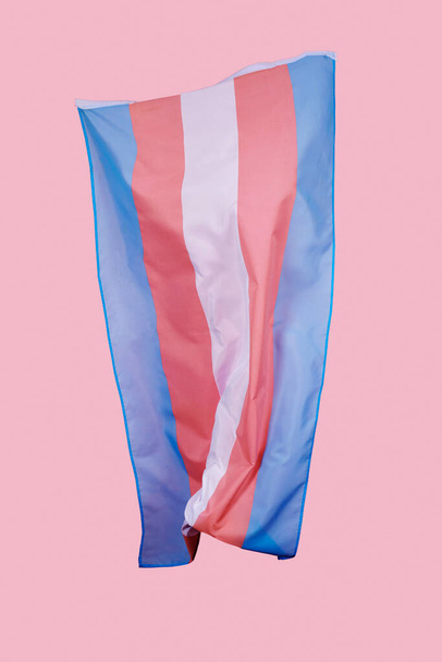 Eine Flagge des Transgender-Stolzes weht in der Luft auf rosa Hintergrund - Foto, Bild