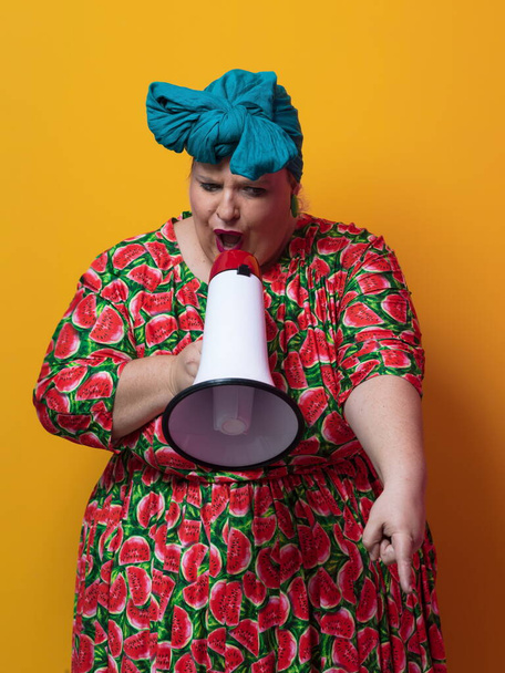 Funny plus size woman posing isolated on yellow background studio portrait. Overweight lady screaming in a megaphone. People emotions lifestyle concept. Mock up copy space. - Foto, Imagem