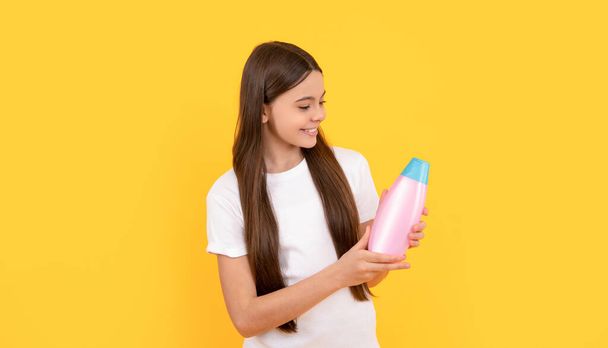 szczęśliwy dziecko trzymać szampon butelka na żółtym tle, piękno - Zdjęcie, obraz