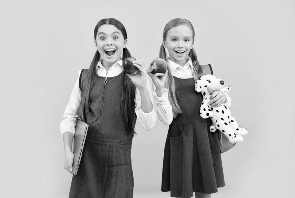 Los escolares en uniformes formales mantienen la boca abierta de sorpresa con manzanas naturales, alimentación saludable - Foto, Imagen