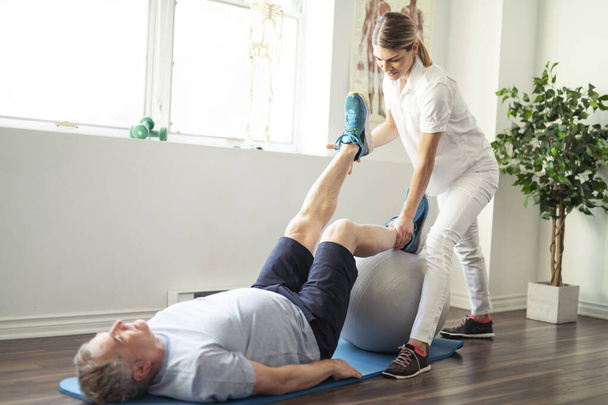 A Modern rehabilitation physiotherapy worker with senior client - Фото, изображение