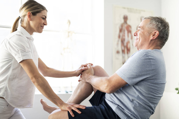 A Modern rehabilitation physiotherapy worker with senior client - Photo, Image