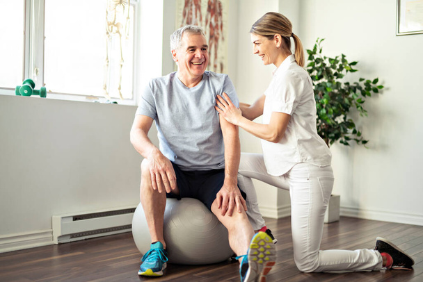 A Modern rehabilitation physiotherapy worker with senior client - Fotoğraf, Görsel