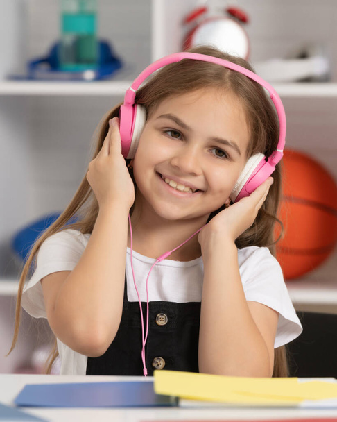 χαρούμενο παιδί να ακούει μουσική σε ακουστικά στην σχολική τάξη - Φωτογραφία, εικόνα
