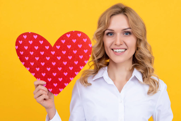 happy woman with red love heart on yellow background. charity - Foto, Imagen