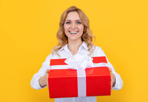 smiling woman with big present box on yellow background - Фото, зображення