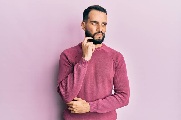 Giovane uomo con la barba indossa maglione invernale casual pensando concentrato sul dubbio con il dito sul mento e guardando verso l'alto chiedendo  - Foto, immagini