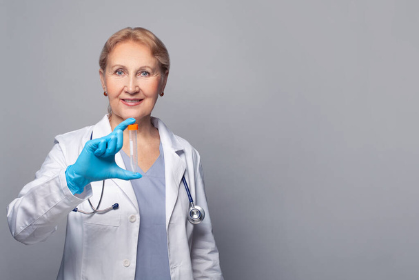 Lächelnde Ärztin im Laborkittel mit Reagenzglas vor blauem Banner-Hintergrund - Foto, Bild