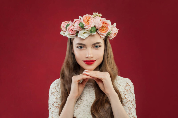Healthy woman with clean skin in summer flowers on her head against red wall background - Фото, зображення