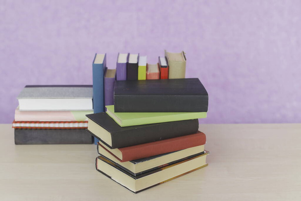 Stack of books on violet background - Foto, afbeelding