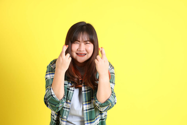 The chubby Asian woman standing on the yellow background with the casual clothes. - Photo, image