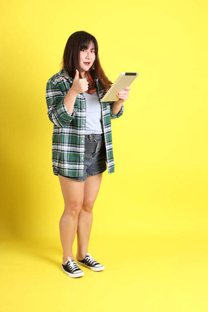 The chubby Asian woman standing on the yellow background with the casual clothes. - Foto, Bild
