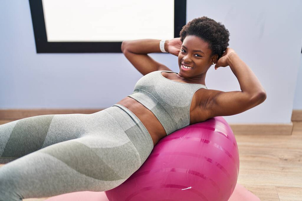 African american woman smiling confident training abs exercise at sport center - 写真・画像