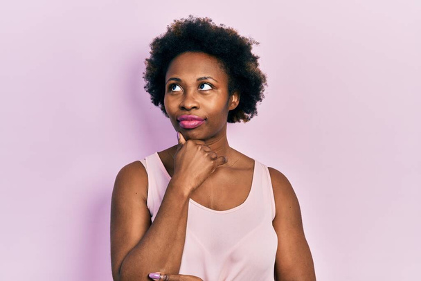 Young african american woman wearing casual sleeveless t shirt with hand on chin thinking about question, pensive expression. smiling with thoughtful face. doubt concept.  - Fotografie, Obrázek