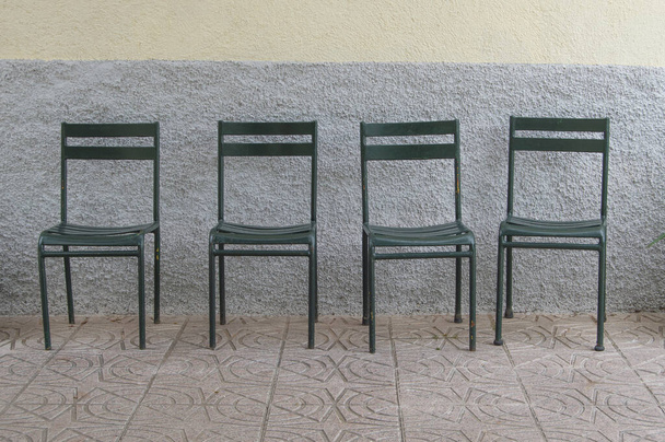set of four metal chairs next to a wall - 写真・画像