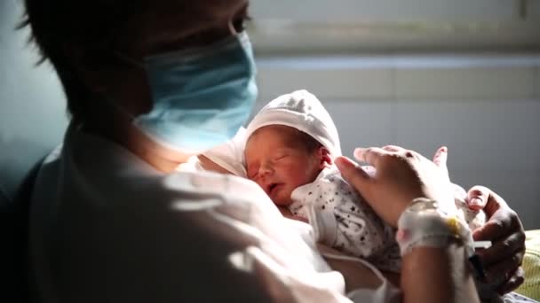 Yeni doğmuş bebeğini tutarken maske takan bir kadın. - Video, Çekim