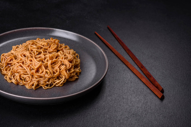 Buckwheat flour noodles with sauce, sesame, herbs and spices on a dark concrete background. Asian cuisine - Foto, Imagem