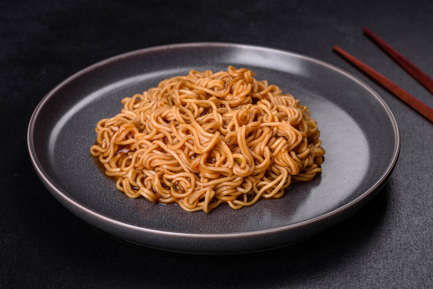 Buckwheat flour noodles with sauce, sesame, herbs and spices on a dark concrete background. Asian cuisine - Фото, изображение
