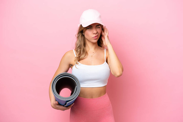 Young sport woman going to yoga classes while holding a mat frustrated and covering ears - 写真・画像