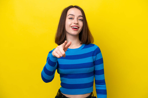 Young Ukrainian woman isolated on yellow background surprised and pointing front - Fotografie, Obrázek
