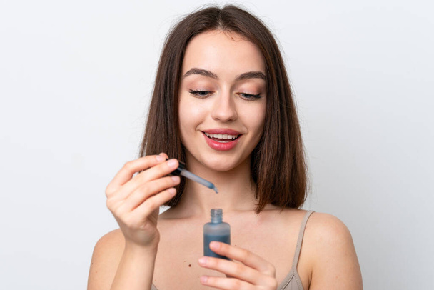 Young Ukrainian woman isolated on white background holding a serum while smiling. Close up portrait - Zdjęcie, obraz