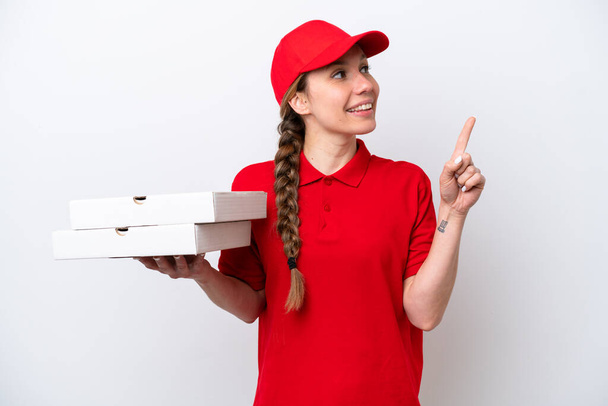 repartidor de pizza con uniforme de trabajo recogiendo cajas de pizza aisladas sobre fondo blanco apuntando a una gran idea - Foto, Imagen