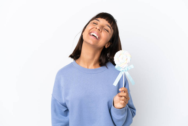 Молодая женщина смешанной расы держит леденец на белом фоне, смеясь - Фото, изображение
