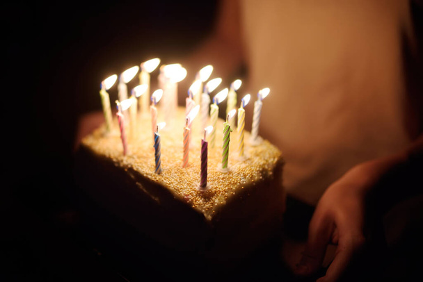 Homemade birthday cake with lots of candles in a dark room. Celebrating birthday at home. - Foto, imagen