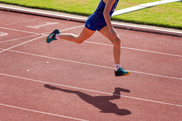 Townsville, Queensland, Australia - Mayo 2022: Una joven corre sobre la línea de meta en atletismo. - Foto, imagen
