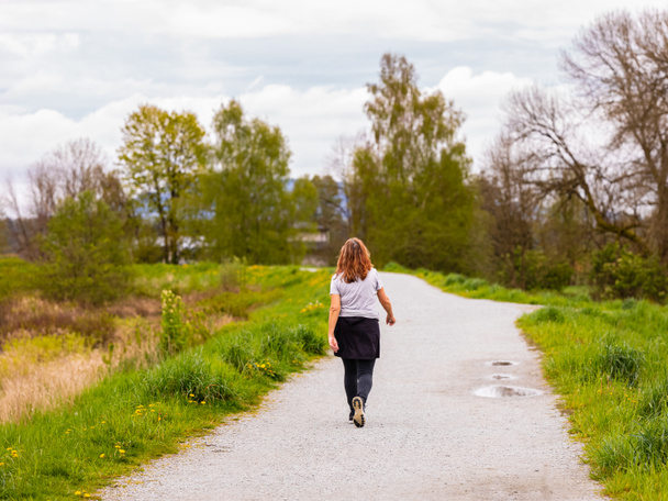 Woman walking in spring forest nature path walk on trail woods background. Happy woman relaxing on active outdoor activity. Street view, travel photo, selective focus - Photo, Image