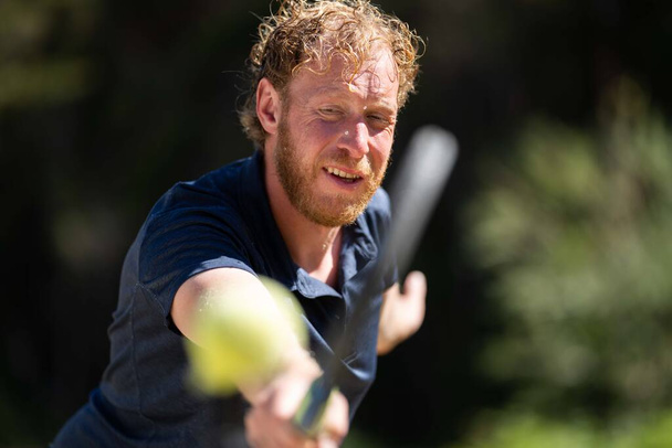 Аматор грає в теніс на турнірі і грає на траві в галявині. - Фото, зображення