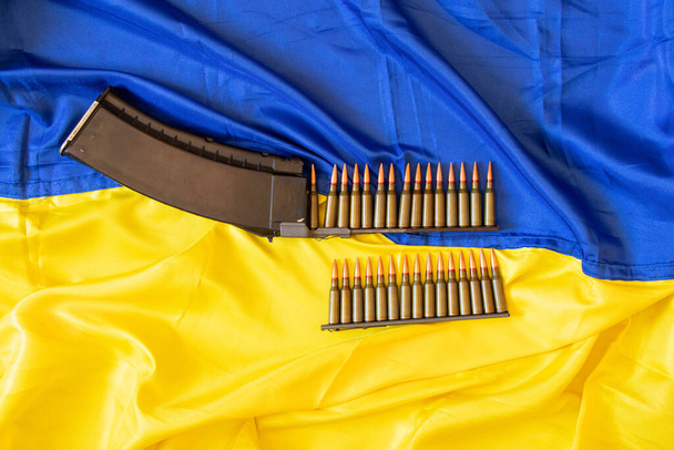 Σφαίρες στην κόρνα κείτονται στην κίτρινη-μπλε σημαία της Ουκρανίας, πόλεμος στην Ουκρανία, άμυνα της πατρίδας, όπλα, σφαίρα 2022 - Φωτογραφία, εικόνα
