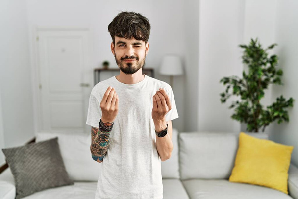 Hispánec s plnovousem v obýváku doma dělá gesto peněz rukama, žádá výplatu mzdy, milionářský byznys  - Fotografie, Obrázek