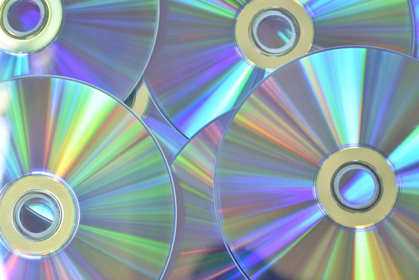 CD ou DVD com reflexão de luz colorida na superfície em fundo branco
 - Foto, Imagem