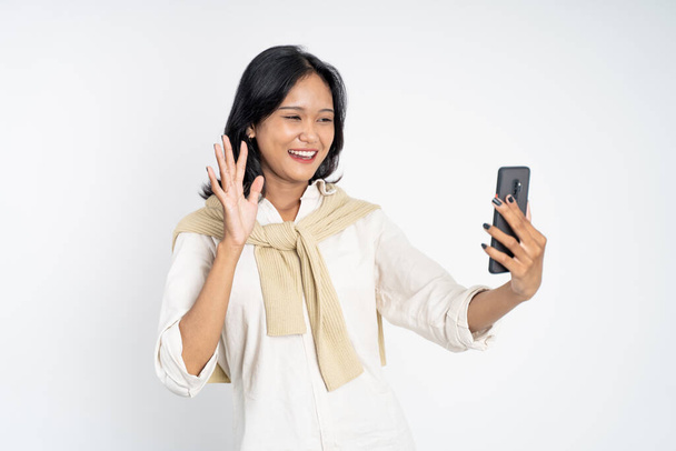donna fare una videochiamata utilizzando il telefono cellulare con dire ciao gesto - Foto, immagini