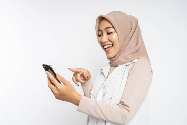 excited asian woman laugh with finger pointing on her mobile phone - Zdjęcie, obraz
