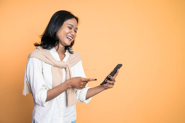 excited asian woman laugh with finger pointing on her mobile phone - Foto, Imagem