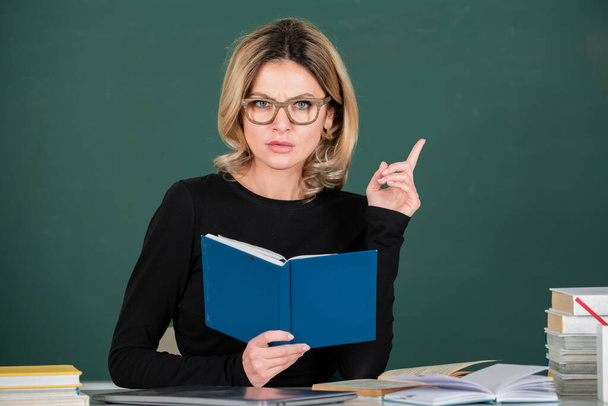 Young female teacher, business woman with books on chalkboard in classroom. - Fotoğraf, Görsel