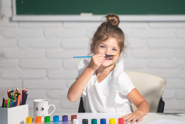 Child girl drawing with coloring pens paintind. Portrait of adorable little girl smiling happily while enjoying art and craft lesson in school. Kids creative education concept - Фото, изображение