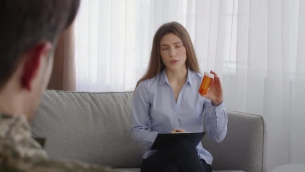 PTSD treatment. Professional woman psychologist prescribing antidepressants for unrecognizable man soldier - Séquence, vidéo