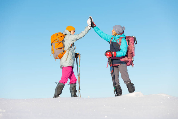 Dwie kobiety chodzą w śnieżnych butach, zimą trekking, dwie osoby w górach zimą, sprzęt turystyczny, przybicie piątki - Zdjęcie, obraz