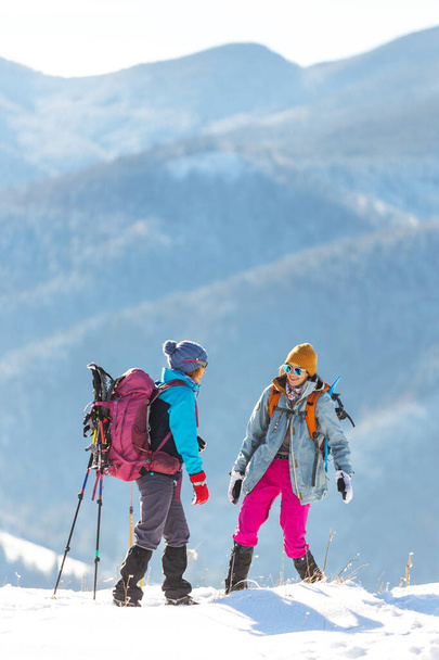twee vrouwen beklommen de top van de berg tijdens een winterwandeling, wintertrekking, twee vriendinnen reizen samen, besneeuwde bergen - Foto, afbeelding